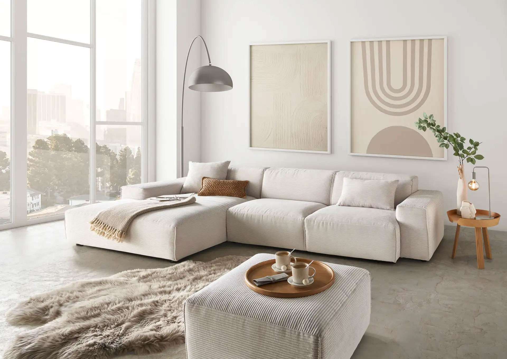 Modernes helles Wohnzimmer mit beigem Ecksofa und passendem Hocker, Bogenlampe, abstrakten Wandbildern in Erdtönen, großen Fenstern und minimalistischer Einrichtung