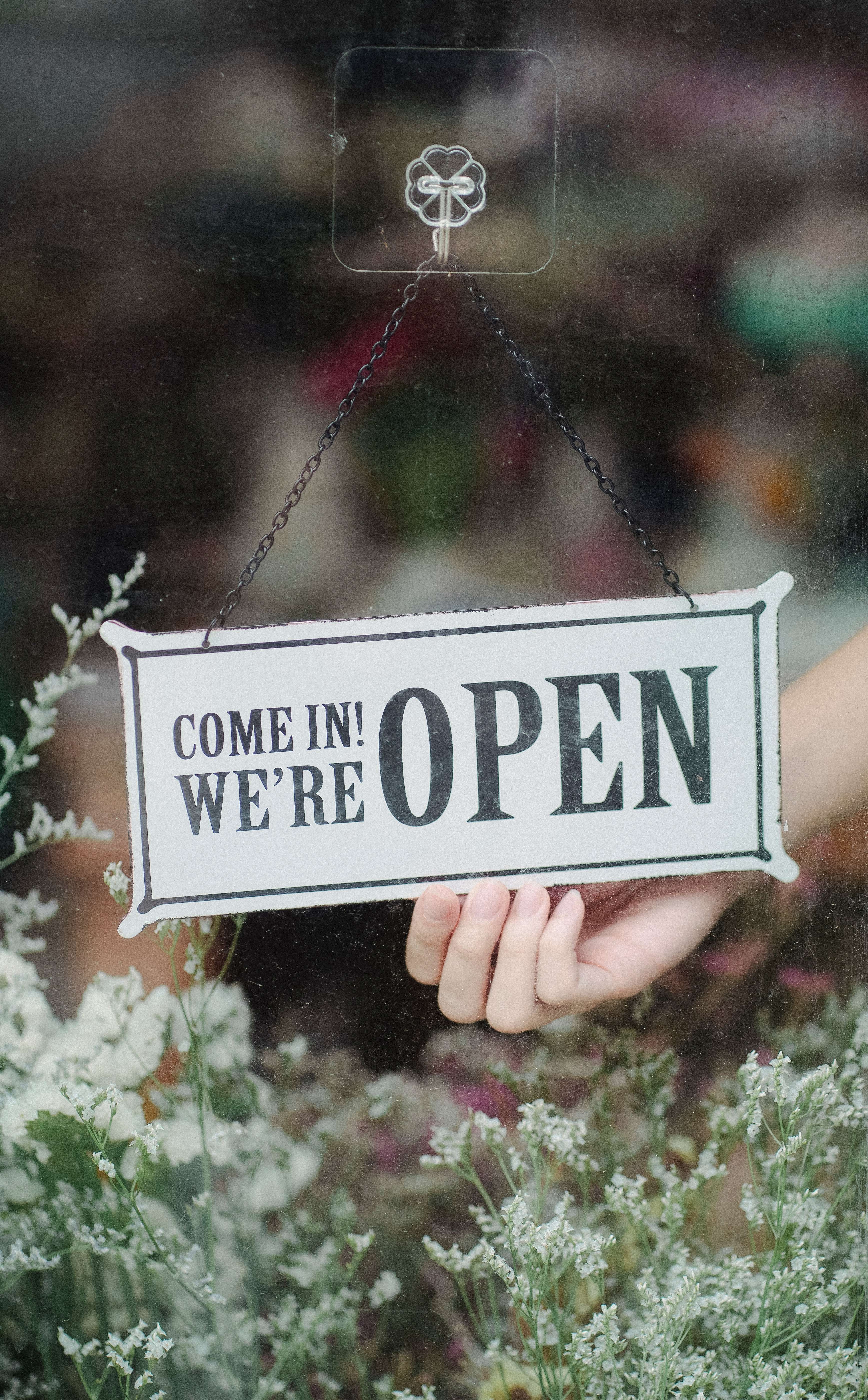 Eine Glastür mit einem Schild das die Aufschrift "Come in we are open" trägt