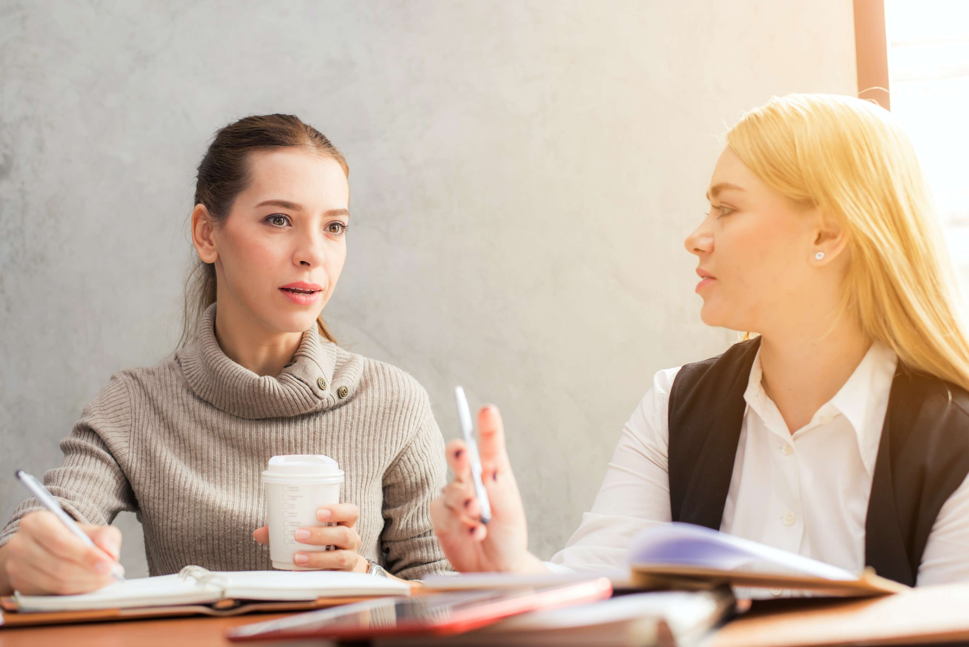 Zwei junge Frauen unterhalten sich an einem Tisch