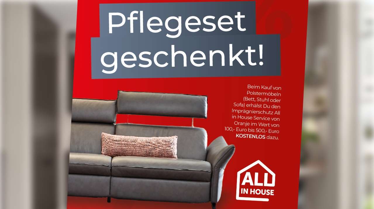 Rotes Werbeplakat mit grauem Polstersofa und dem Hinweis auf ein kostenloses Pflegeset beim Möbelkauf.