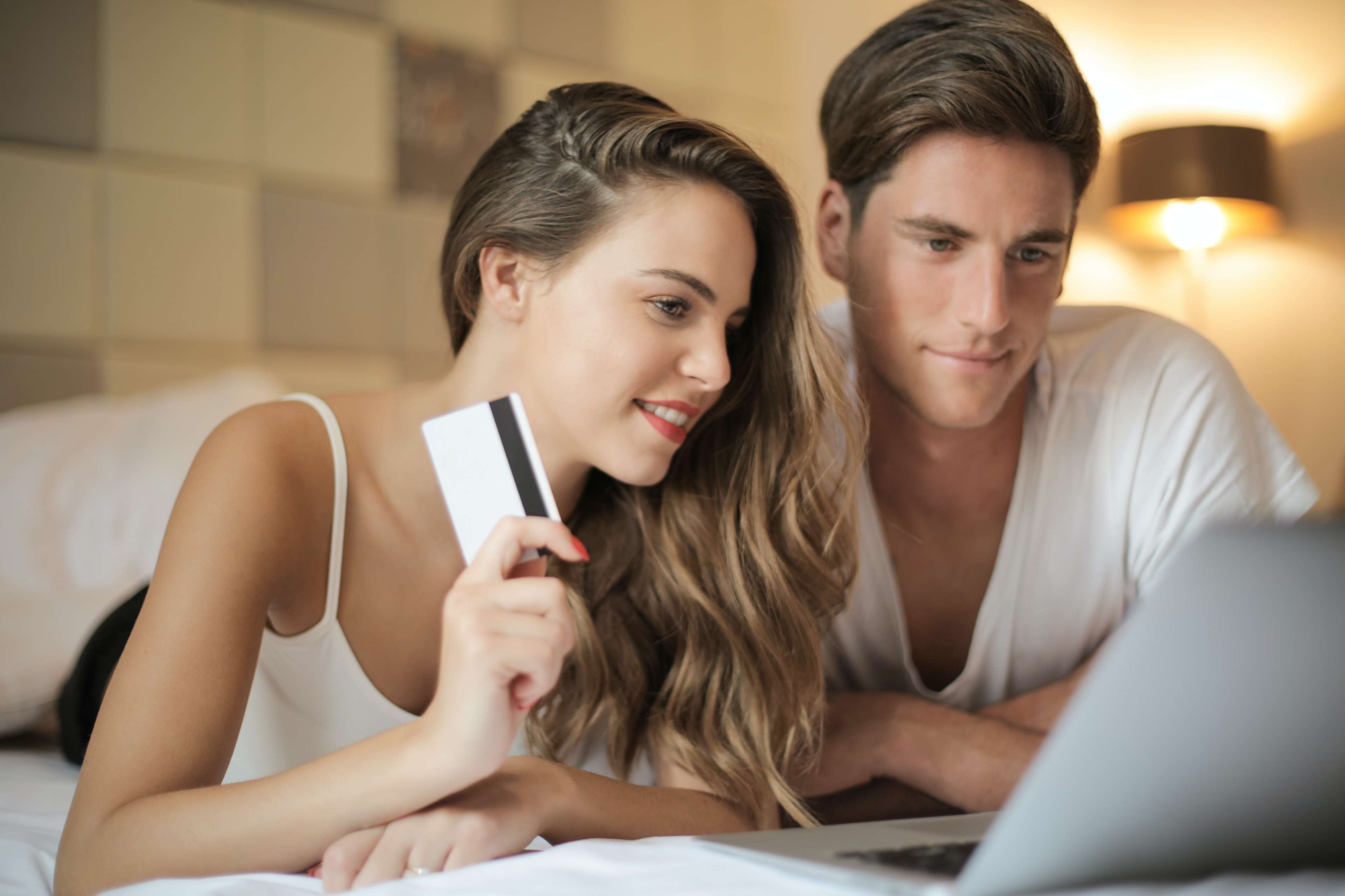 Junges Paar shoppt im Internet mit einer Kreditkarte im der Hand