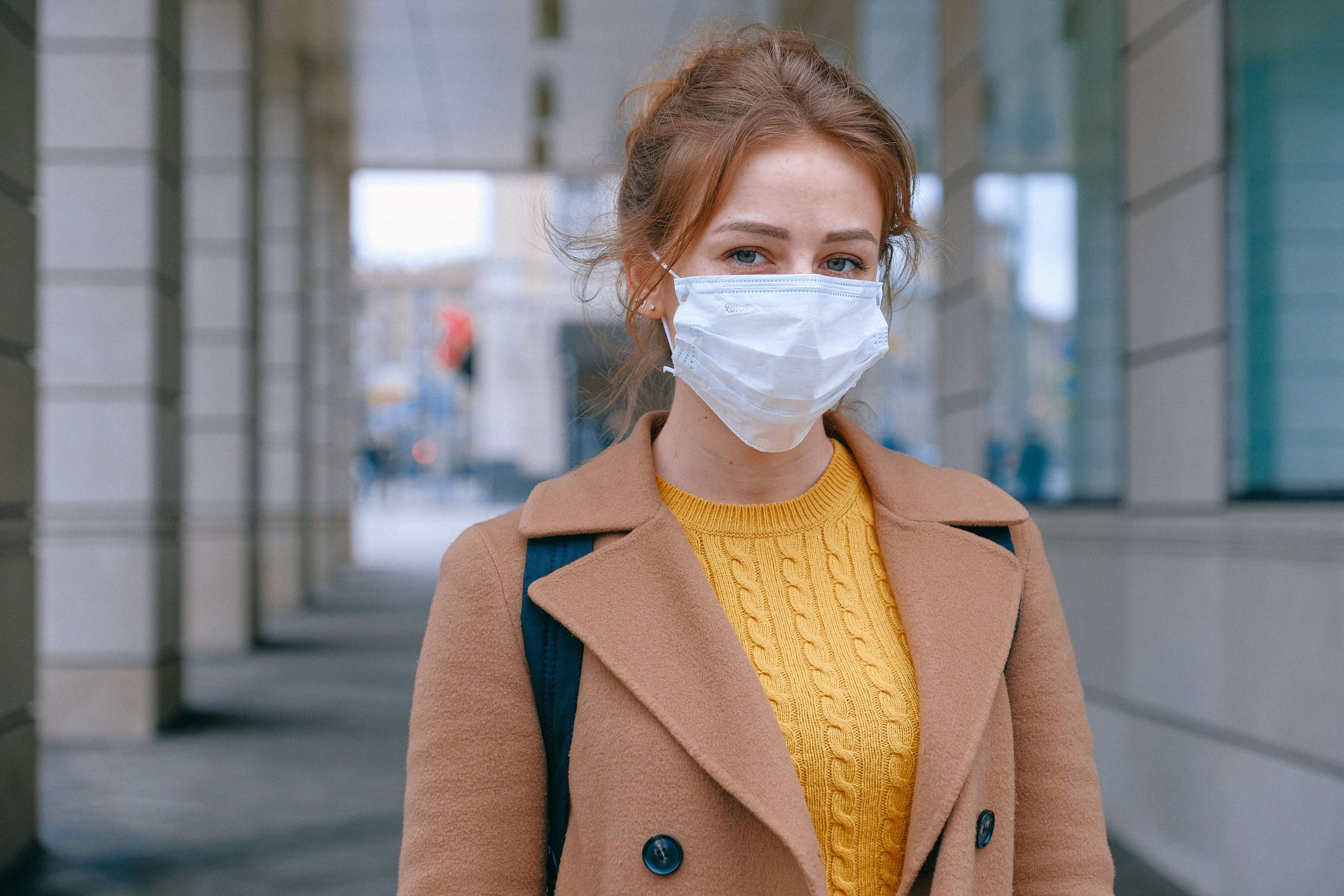 Junge Frau steht auf der Straße und trägt einen medizinischen Mundschutz