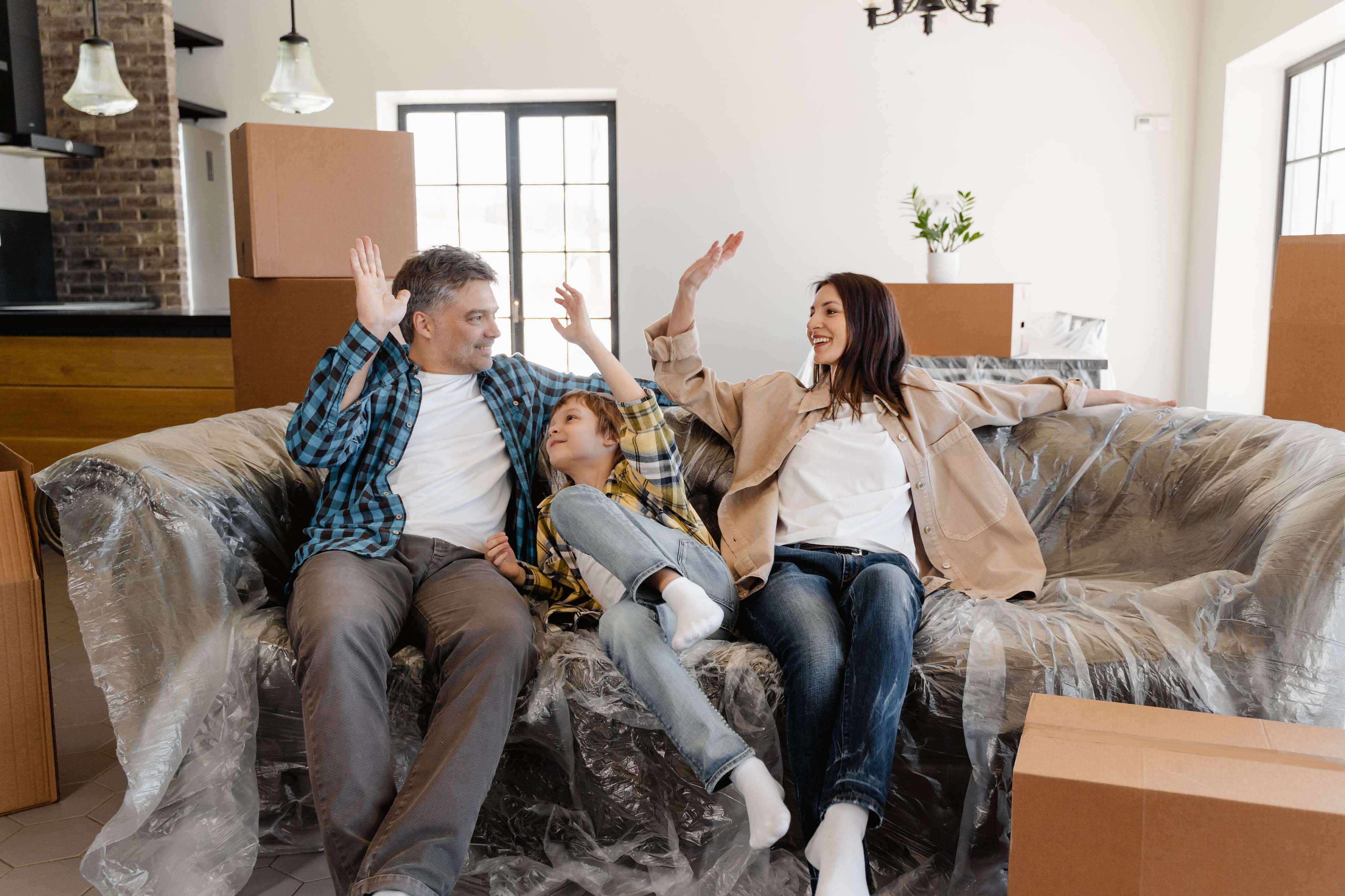Familie macht High-Five auf Ihrer neuen Couch zwischen Umzugskartons